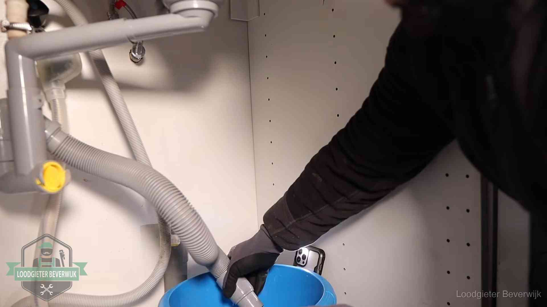 Afvoerslang loopt leeg in een emmer onder de gootsteen in Beverwijk, een klus die je zelf kunt doen