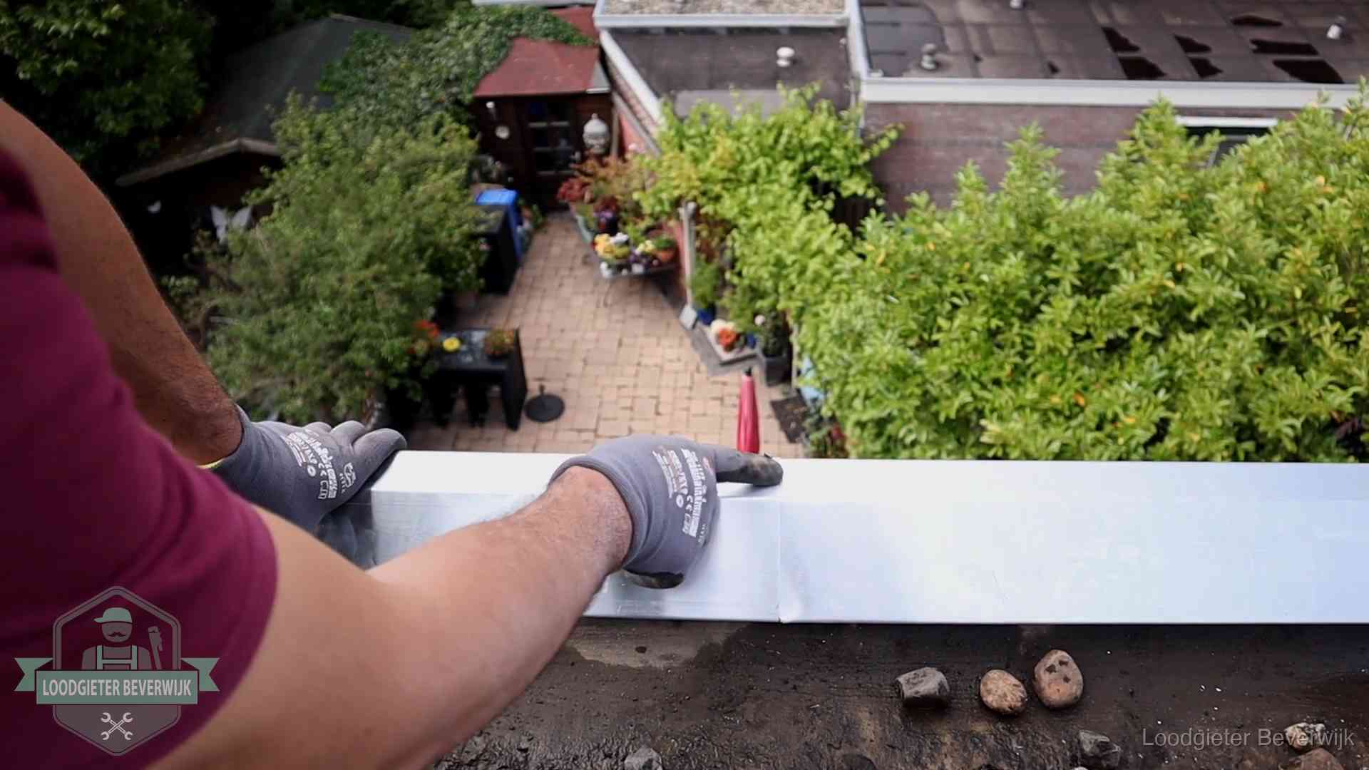 Daklekkage geregeld in Beverwijk Vakman plaatst een daktrim op de dakrand van een woning in Beverwijk