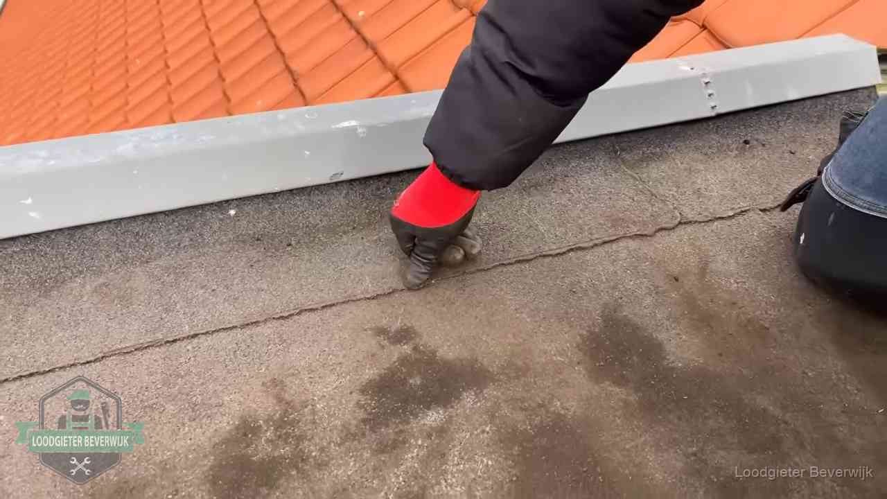 Lekkage bij de naad van een plat dak in Beverwijk Vakman wijst een naad met vochtplekken aan op een bitumen plat dak in Beverwijk
