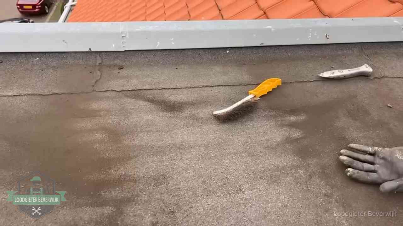 Kosten van daklekkage-reparatie in Beverwijk Dakdekker bereidt een bitumen plat dak voor op reparatie bij de daktrim in Beverwijk