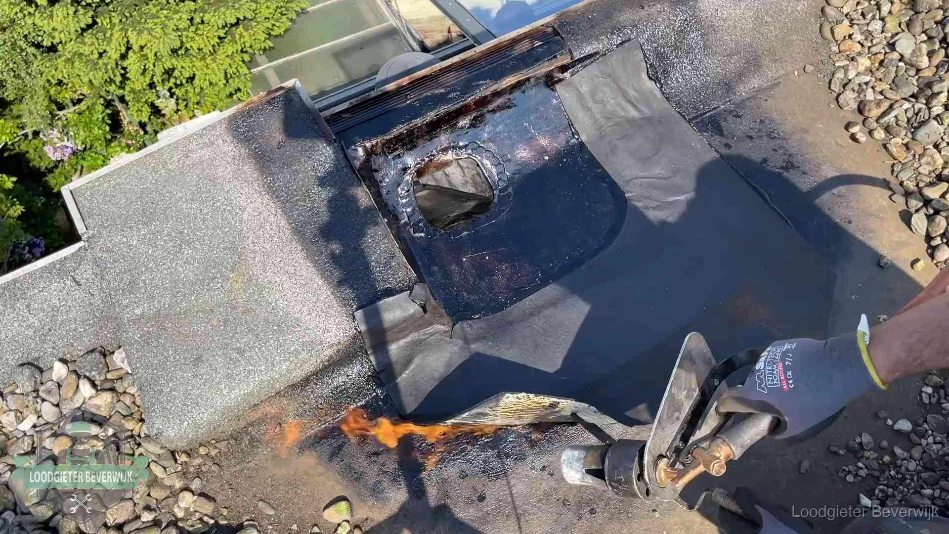 Daklekkage repareren in Beverwijk Dakdekker brandt bitumen rond een doorvoer tijdens een daklekkage-reparatie in Beverwijk