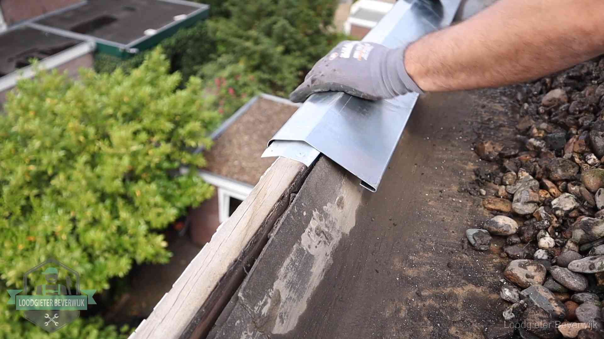 Daklekkage per wijk in Beverwijk Dakdekker plaatst een zinken deklijst op een dakrand met uitzicht over een woonwijk in Beverwijk