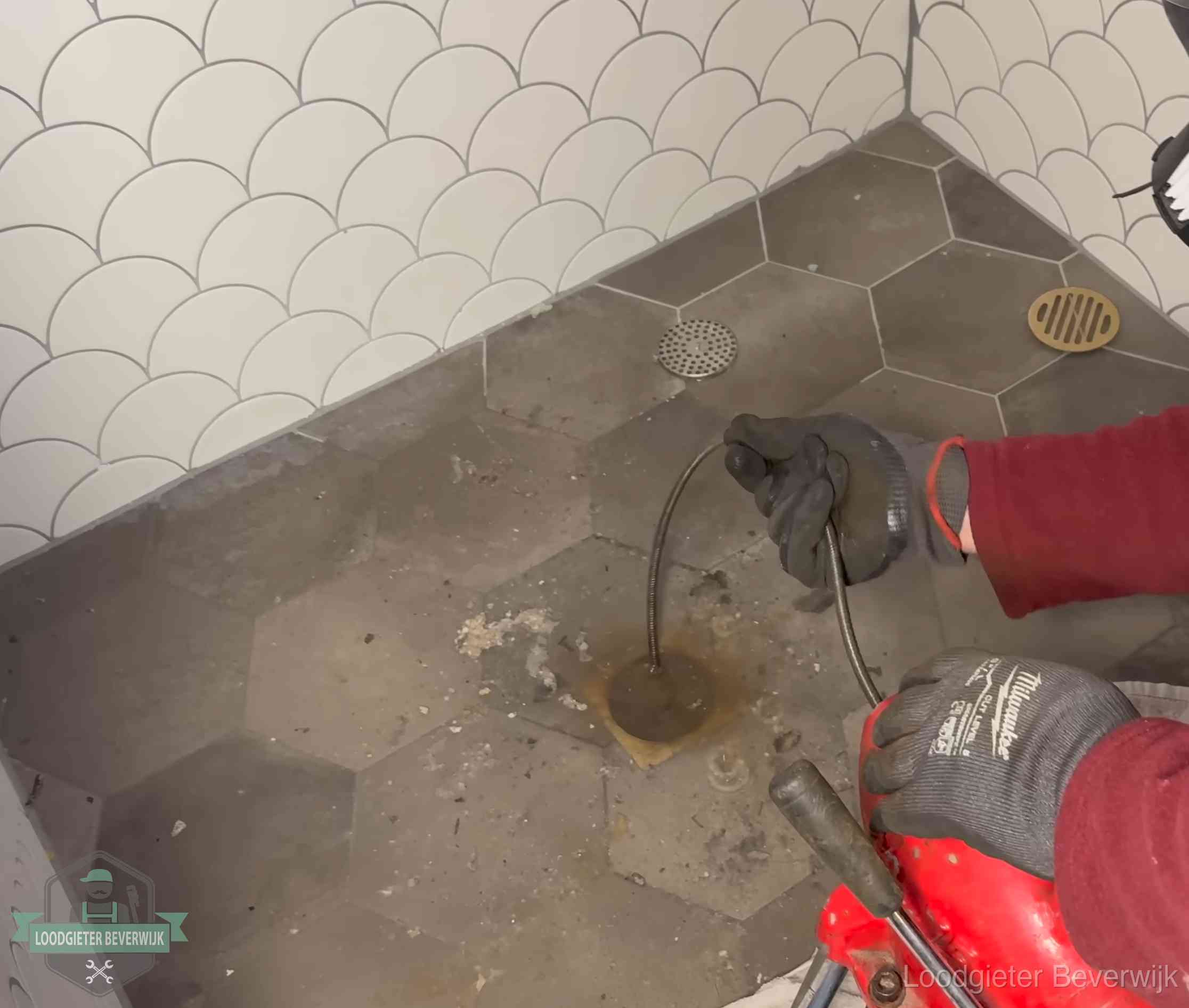 Ontstoppingsveer gaat in een geopend doucheputje in Beverwijk waar het water omhoogkwam