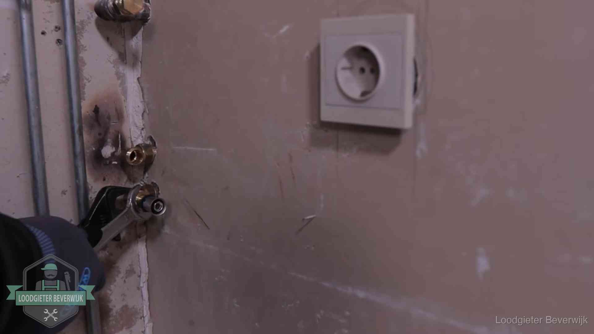 Monteur draait een perskoppeling vast op een leidingaansluiting in Beverwijk