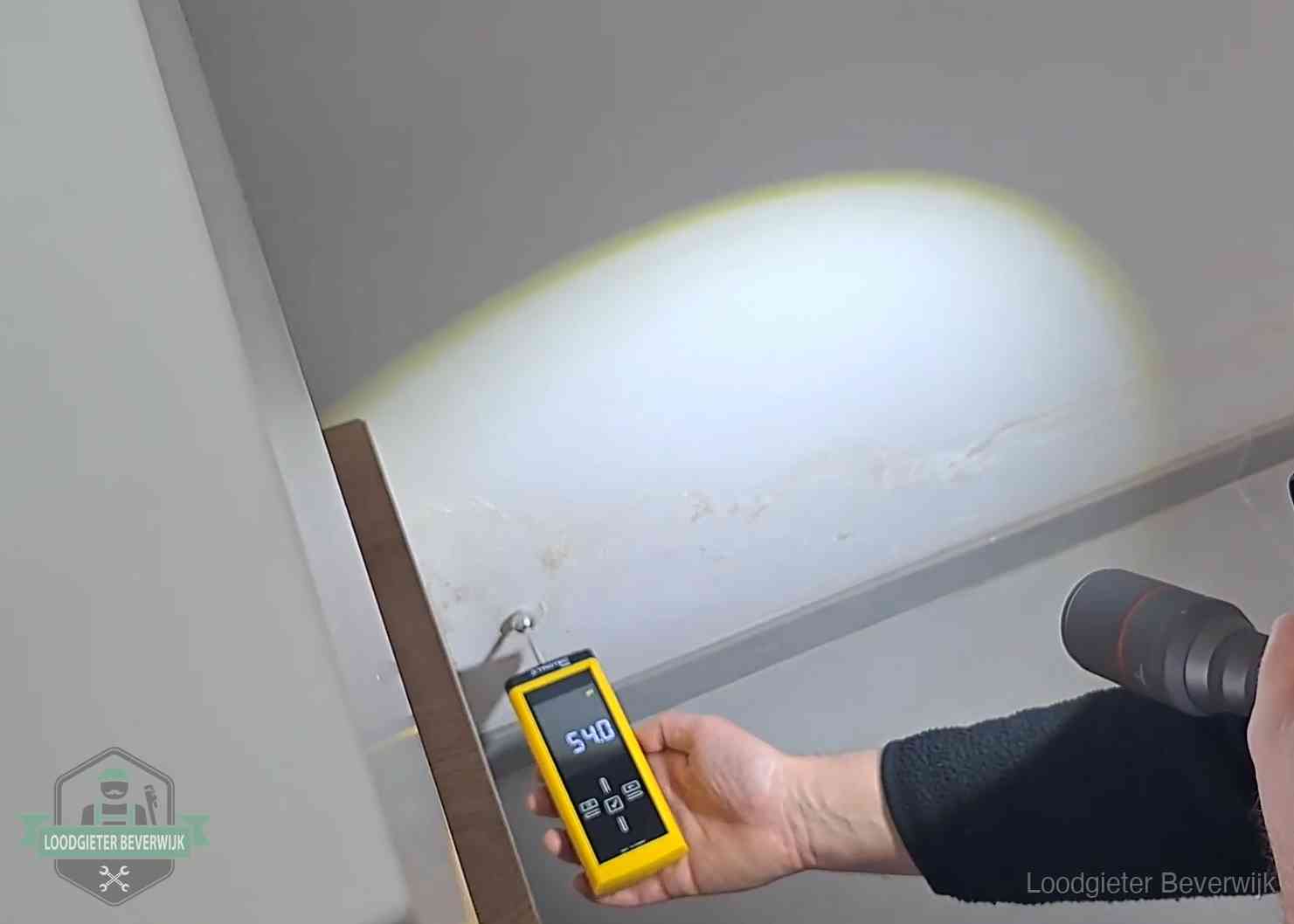 Vochtmeter tegen een natte wand met lekkagesporen in Beverwijk