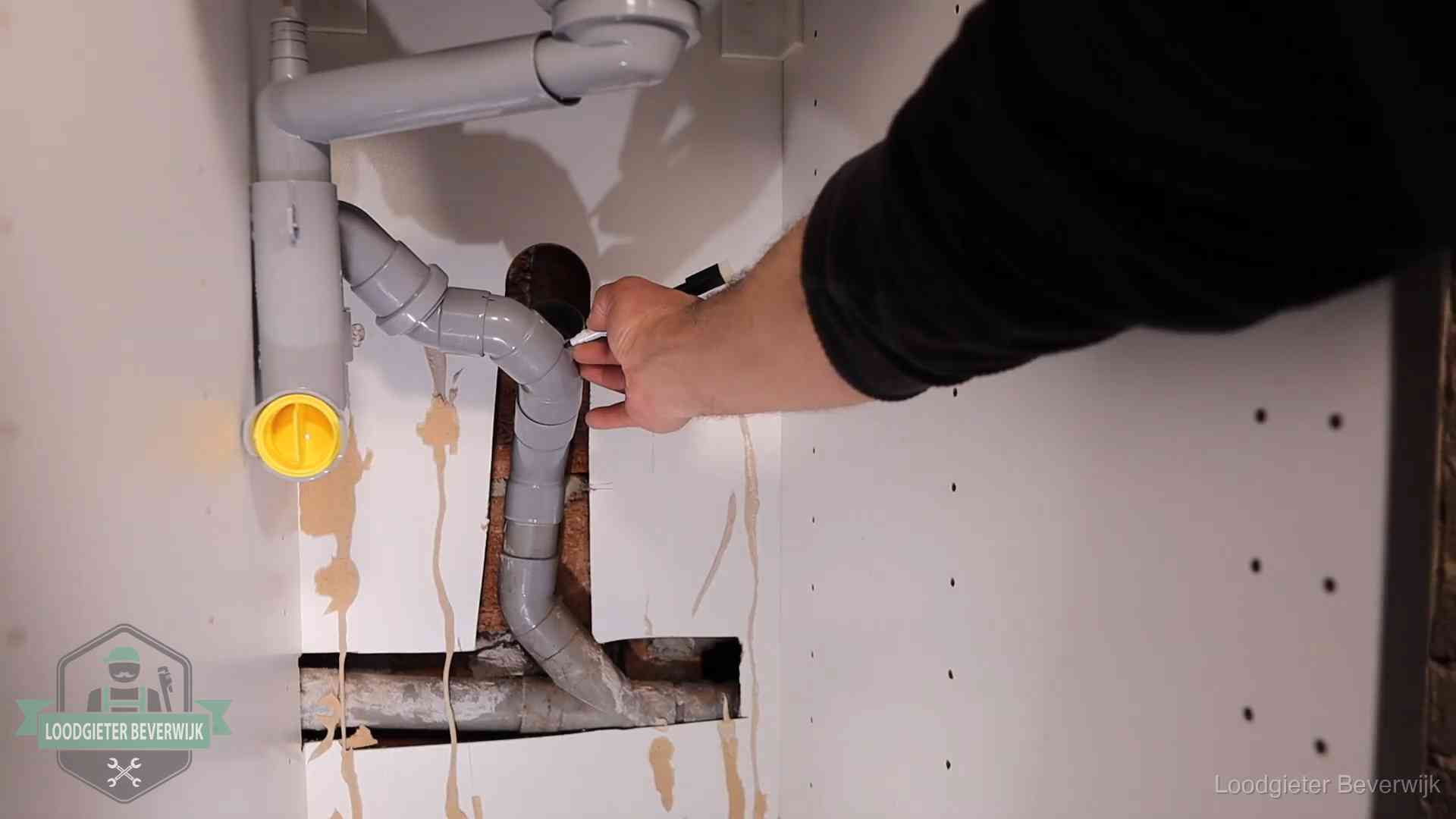Loodgieter markeert een pvc-afvoerbuis onder een gootsteen in Beverwijk