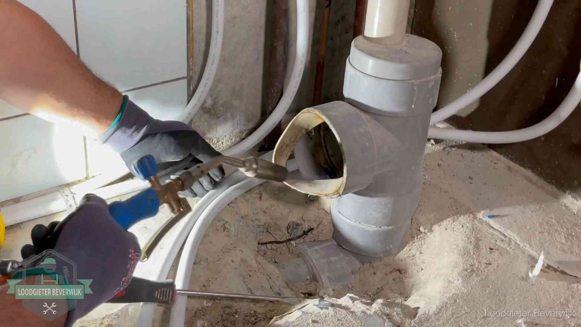 Loodgieter werkt met brander en messing kraanwerk aan leidingen in Beverwijk