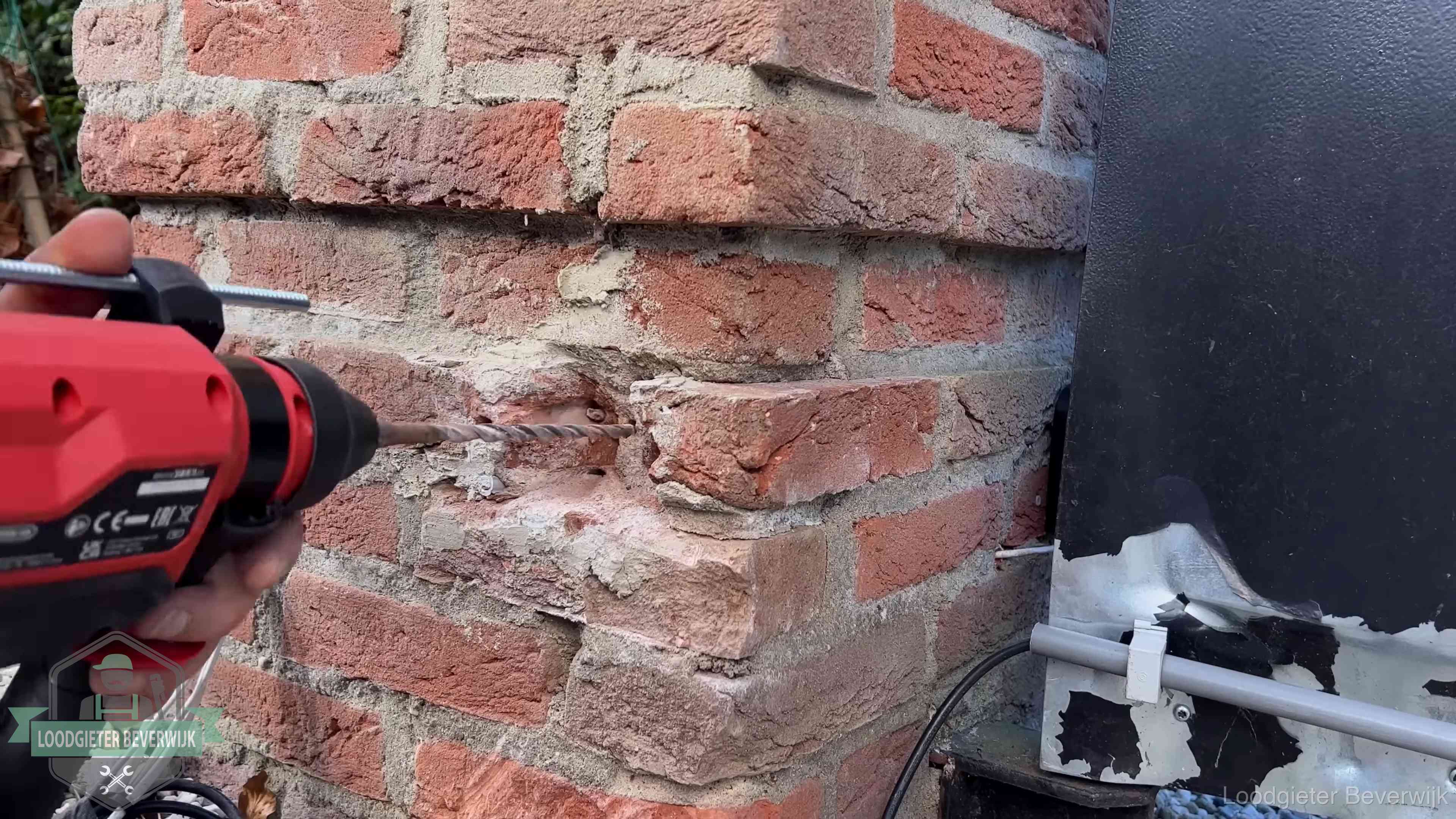 Vakman boort in de buitenmuur van een woning in de regio Beverwijk