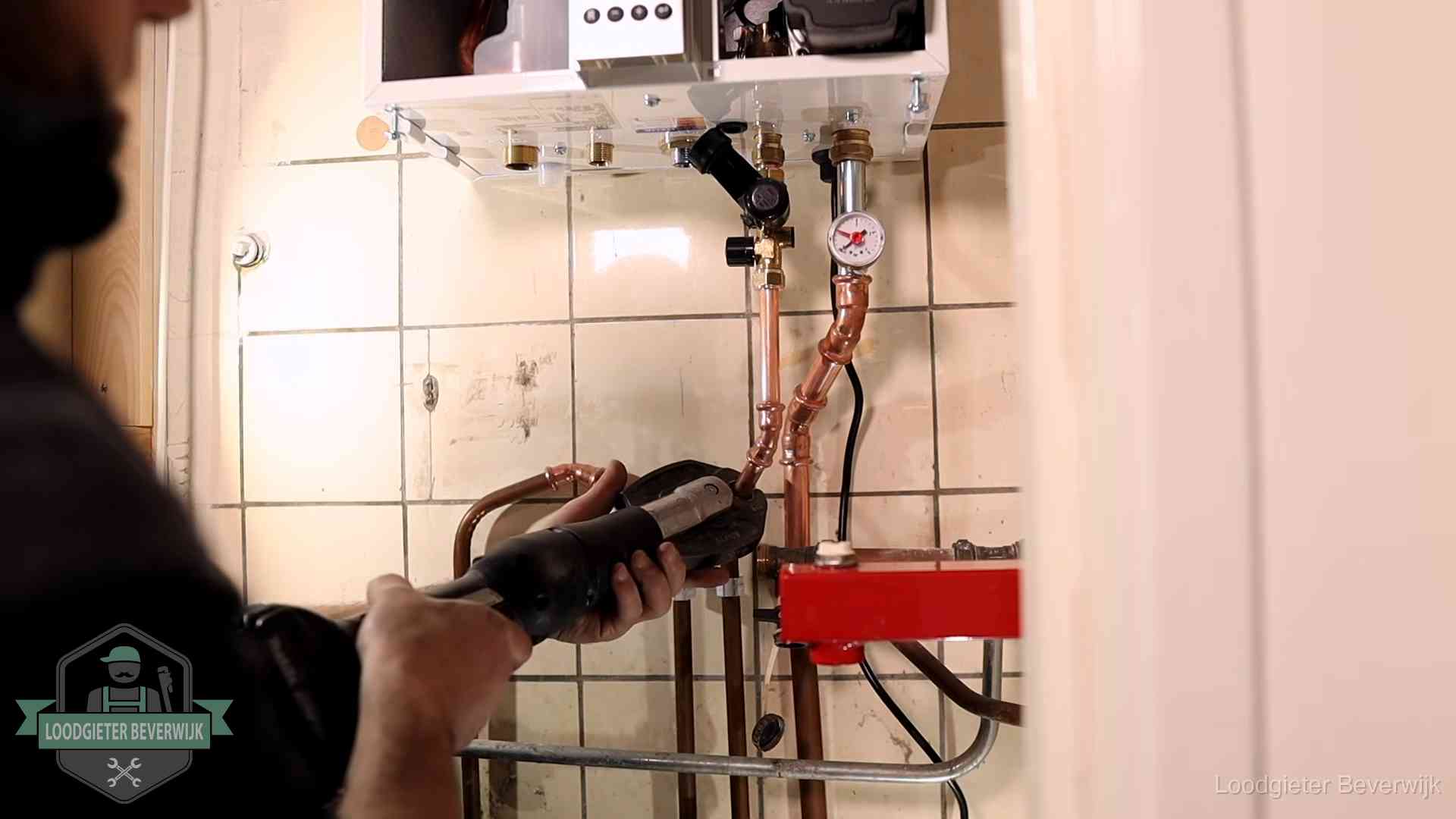 Monteur werkt aan de leidingen onder een cv-ketel in Beverwijk