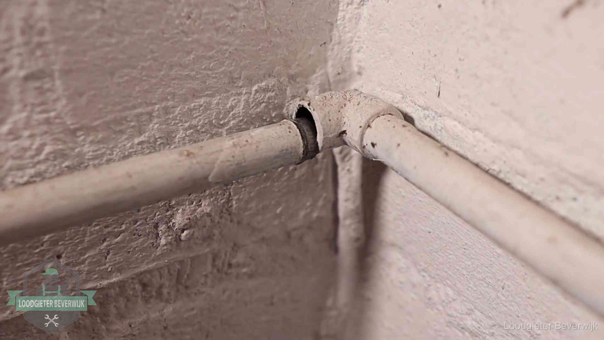 Oude geverfde waterleiding met een losliggende fitting in een woning in Beverwijk