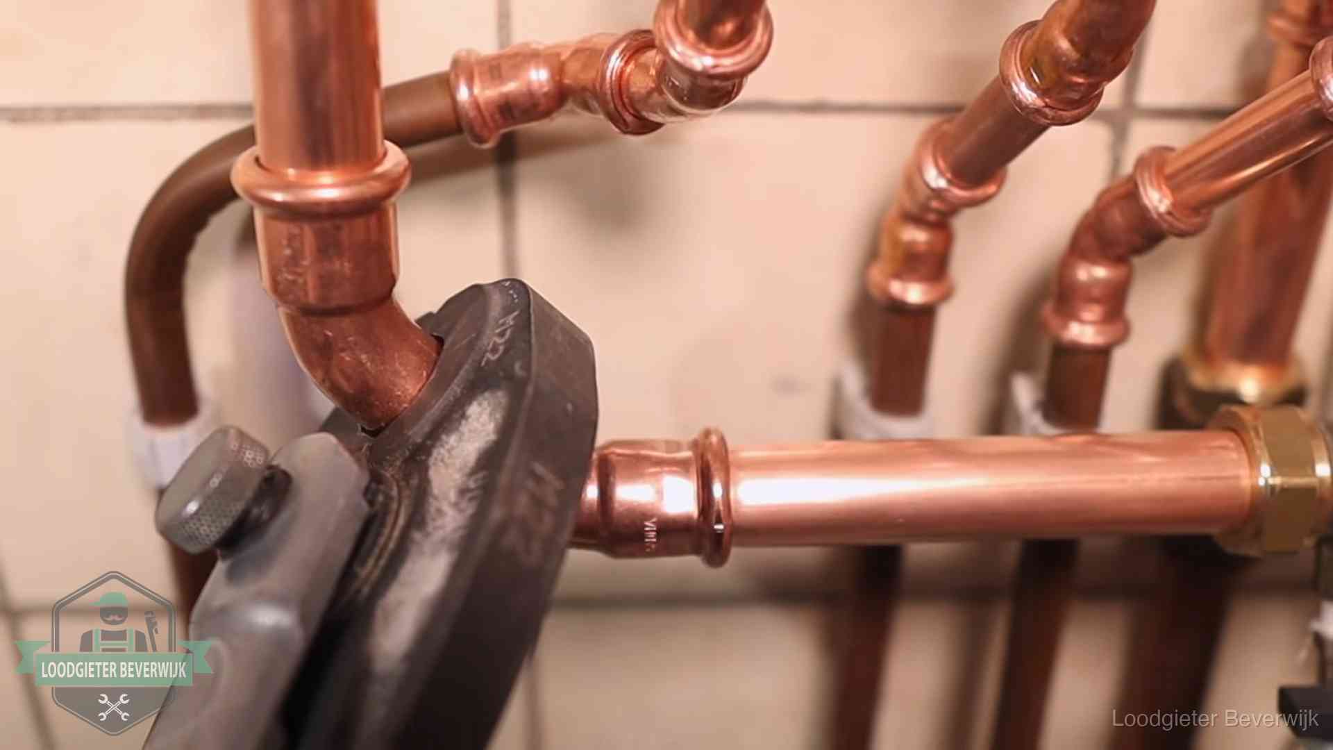 Persmachine perst een koperen fitting op nieuw leidingwerk in Beverwijk