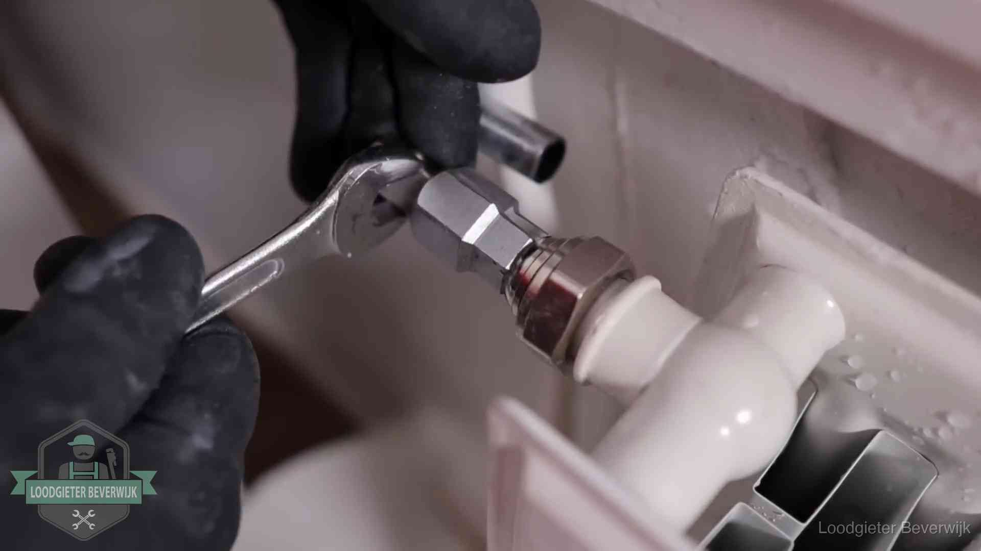 Steeksleutel draait een wartelkoppeling op een radiatorkraan aan in Beverwijk