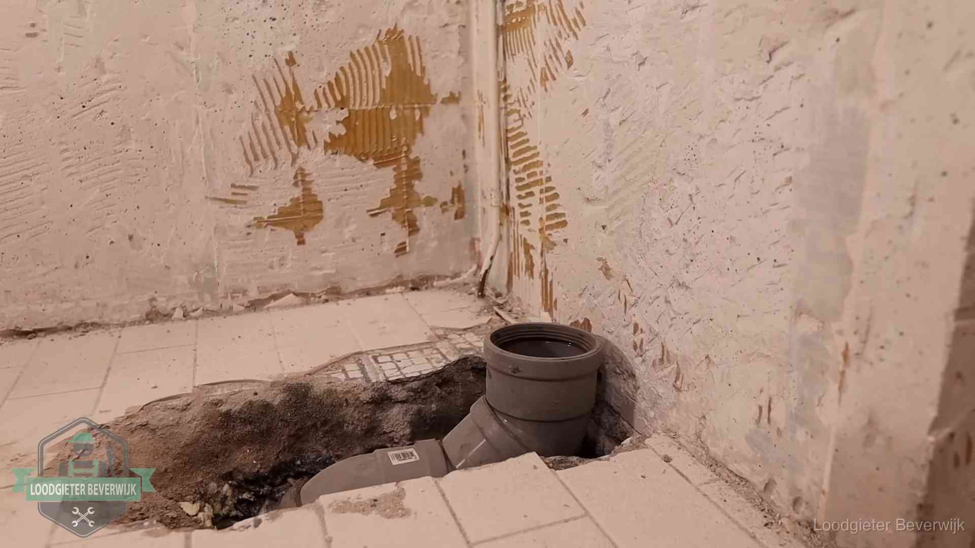 Opengebroken vloer met een nieuwe pvc-rioolbocht in een gegraven sleuf in Beverwijk