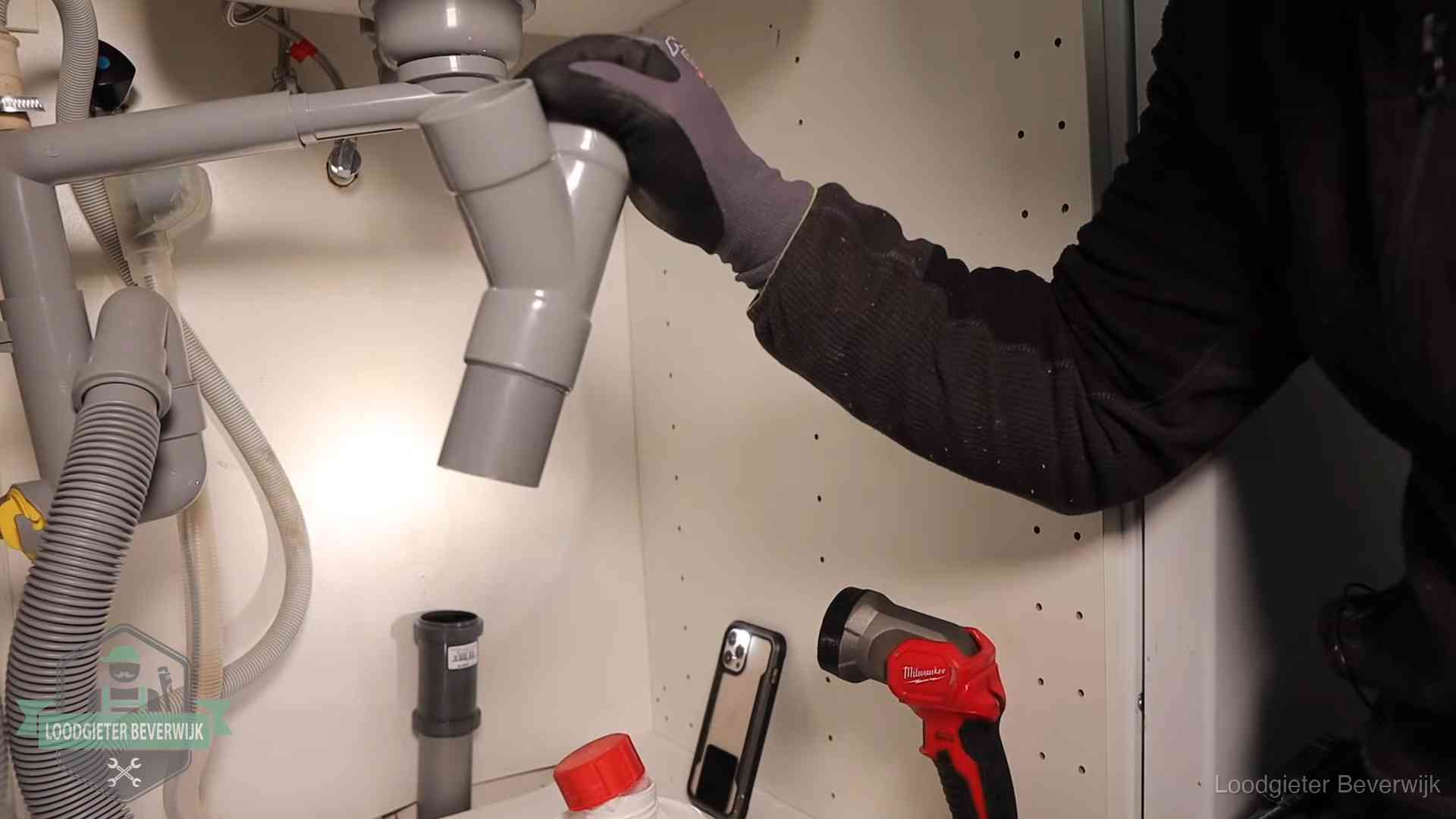 Loodgieter demonteert het sifon- en afvoerwerk onder een gootsteen in Beverwijk bij stankklachten