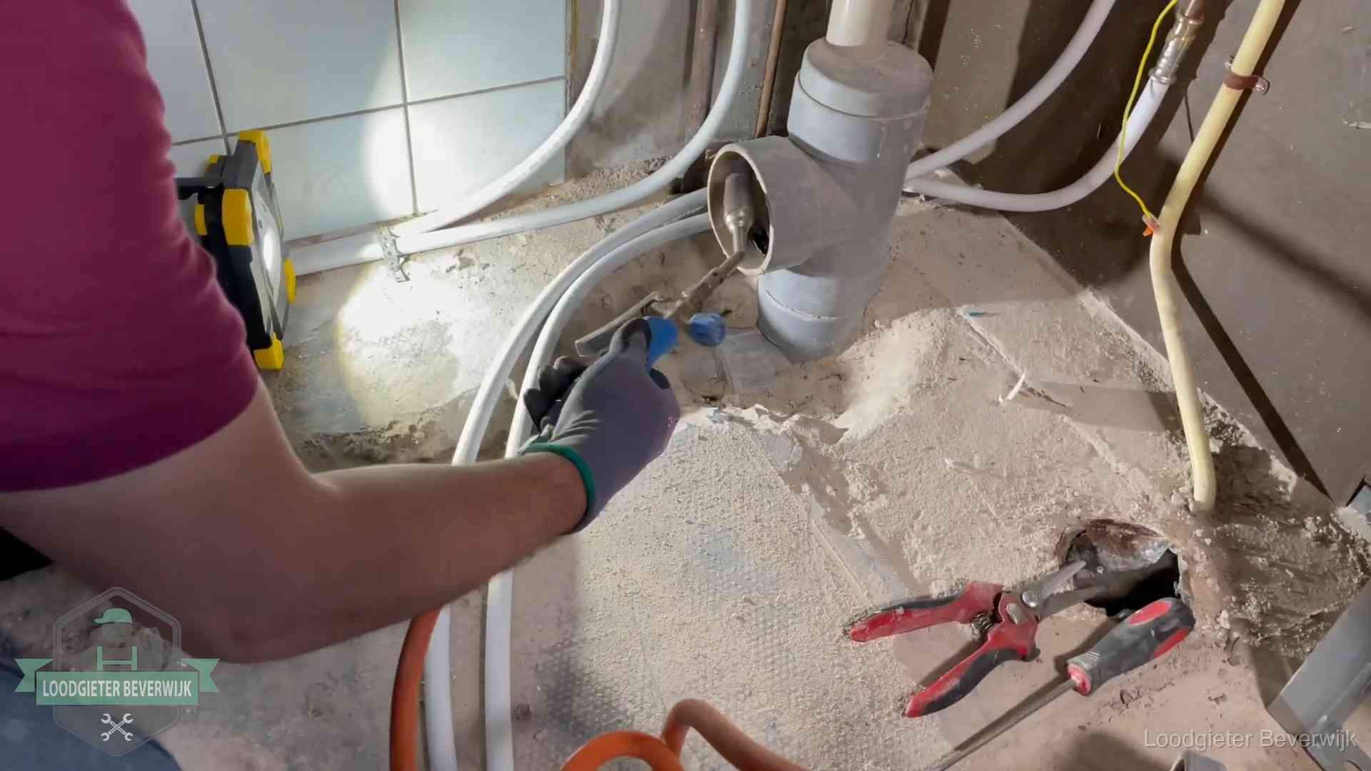Loodgieter werkt aan leidingen bij een pvc-standleiding in een appartement in Beverwijk