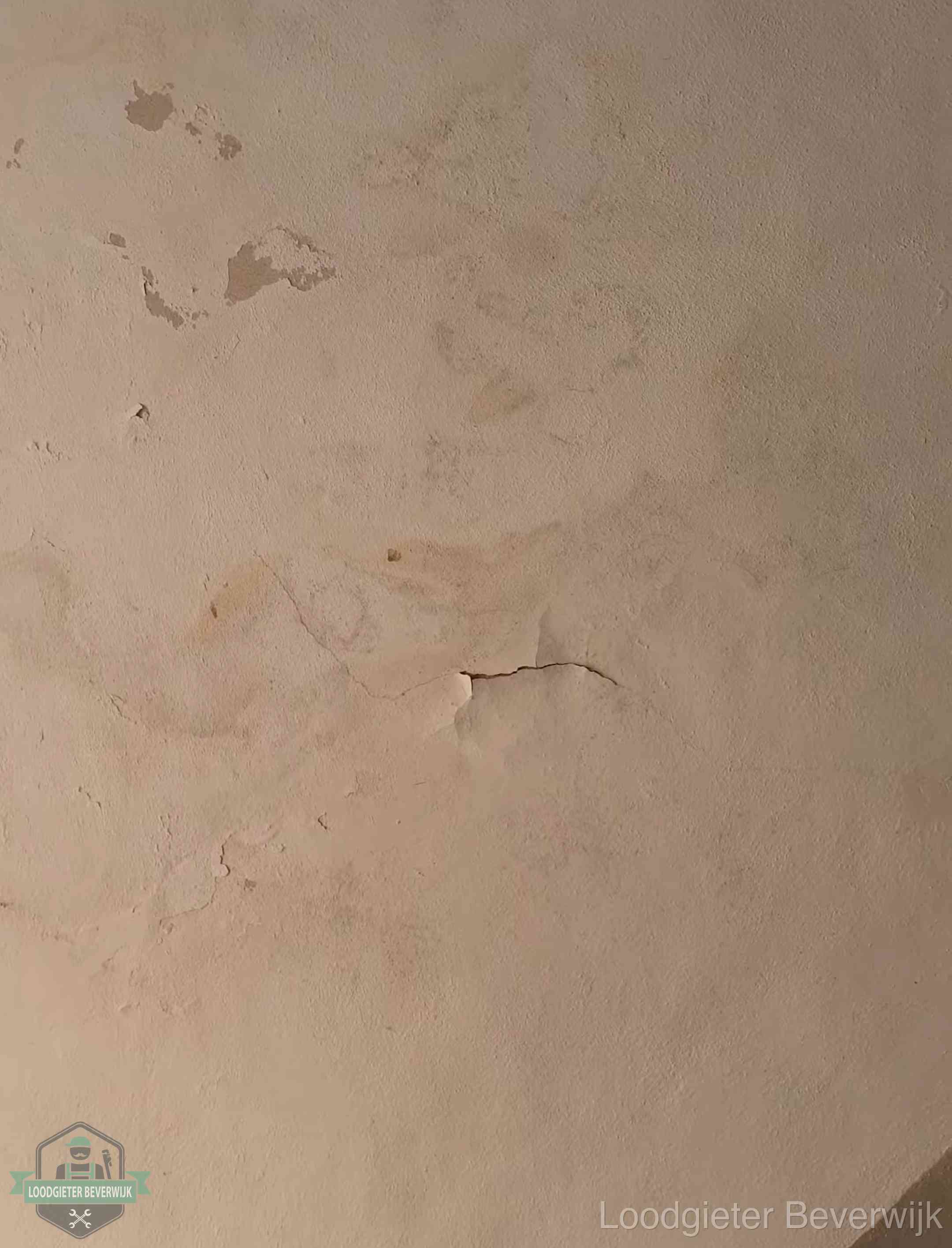 Vochtkringen en afbladderende verf op een plafond in Beverwijk, schade voor het meetrapport en de verzekering