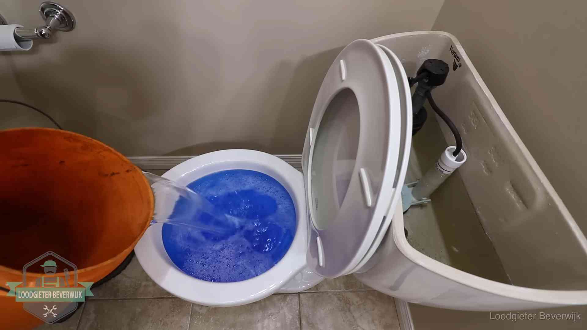 Water bij de wc-pot wordt met een emmer weggewerkt om schade te beperken in Beverwijk